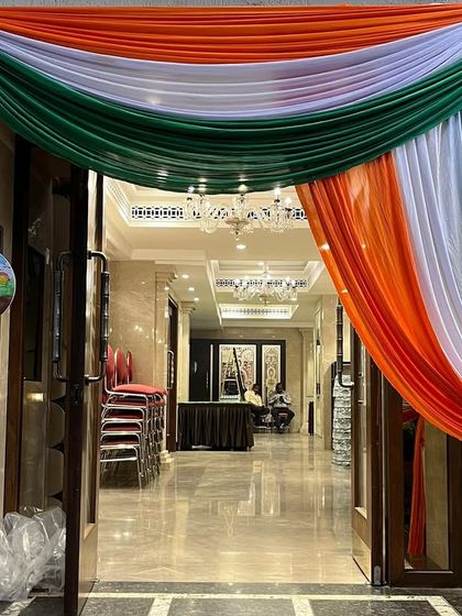 An elegant entrance decoration for a Republic Day celebration. A large, flowing tri-color fabric drape frames the doorway, creating a simple yet powerful patriotic statement.