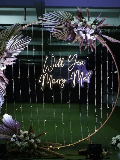 A full view of the modern circular proposal backdrop. This setup is perfect for open spaces, with its elegant gold frame, pampas grass arrangements, and glowing neon sign.