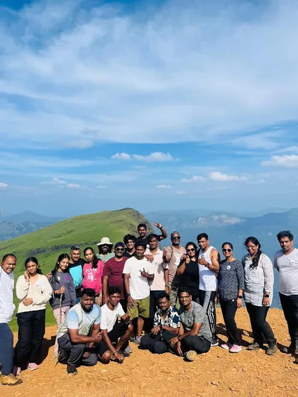 A large group photo at the Netravathi peak on a clear, sunny day. The panoramic view from the top is absolutely breathtaking and a key highlight of this trek.