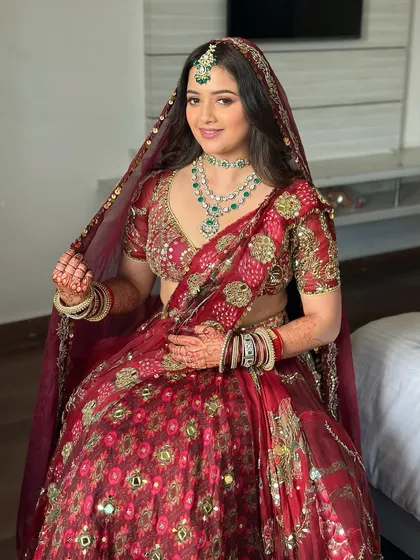 The complete look, with her dupatta set. The soft glam makeup perfectly complements the intricate jewelry and the rich color of her red bridal lehenga.
