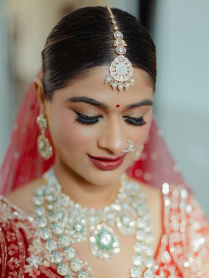 A detailed shot of the bride's eye makeup and jewelry. The winged liner and soft shimmer on the lids make her eyes pop, while the maang tikka draws attention to her flawless base.