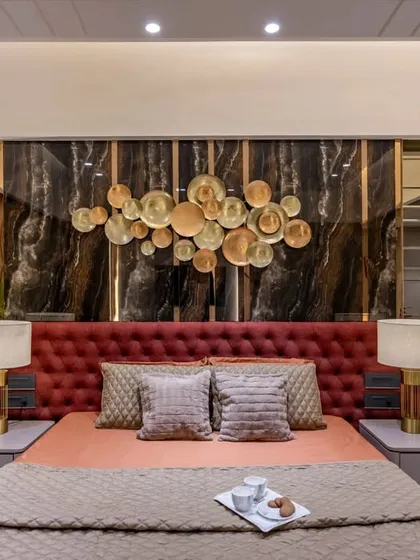 We designed this master bedroom to be a statement of bold elegance. A floor-to-ceiling upholstered headboard in rich crimson is set against a dark marble panel with a bespoke metallic art installation, creating a dramatic and luxurious focal point.