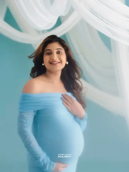 A dreamy, ethereal portrait using flowing fabric and soft light against a blue background.