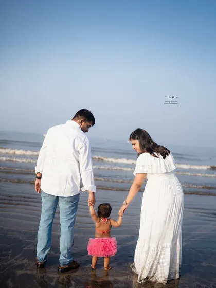 Parents hold their little 'mermaid's' hands as she takes her first steps in the sand. This is a beautiful way to include the whole family in a child's milestone shoot.