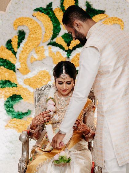 My husband placing a garland on me during the baby shower ceremony. Our coordinated outfits add to the traditional and festive feel of the event.