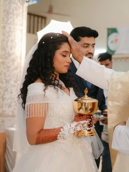 A sacred moment during the ceremony. The bride's makeup is soft and reverent, with a focus on her natural curls and radiant skin.