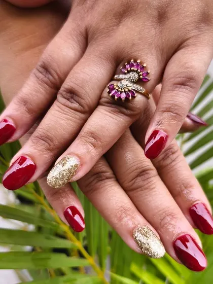Classic party nails featuring temporary extensions with a deep red polish and a full gold glitter accent nail for a touch of glam.
