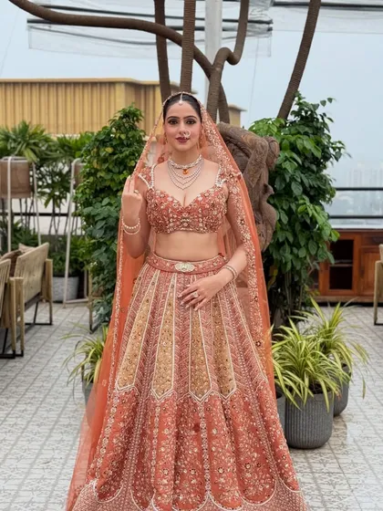 A full-length portrait of my bride in a breathtaking peach and gold lehenga. The soft glam makeup complements the modern color palette, perfect for a day wedding.