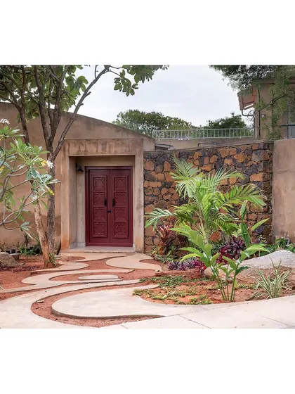 The journey into a home should be memorable. For this farmhouse, I sourced a vintage wine-red door from a village in Andhra. Set against the earthy, natural landscape, it creates a striking focal point and immediately tells a story of history and character, setting the tone for the rest of the home.