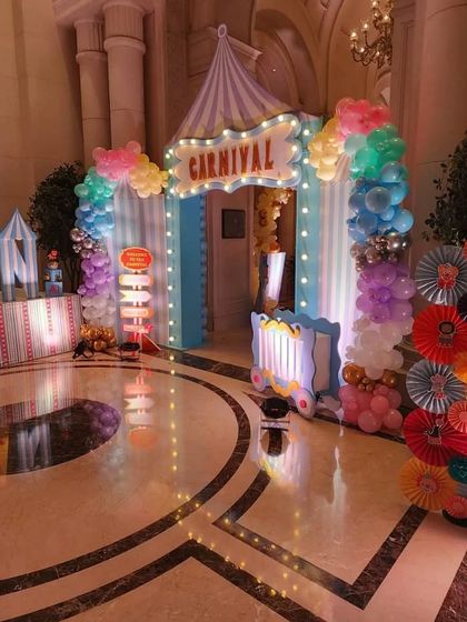 A grand entrance for a Carnival-themed party, with a lighted 'Carnival' sign and colorful props.