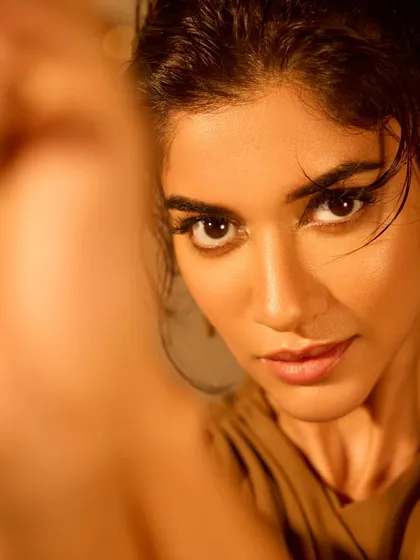 An artistic, over-the-shoulder shot. The focus is on the intense gaze, enhanced by the sharp eyeliner.