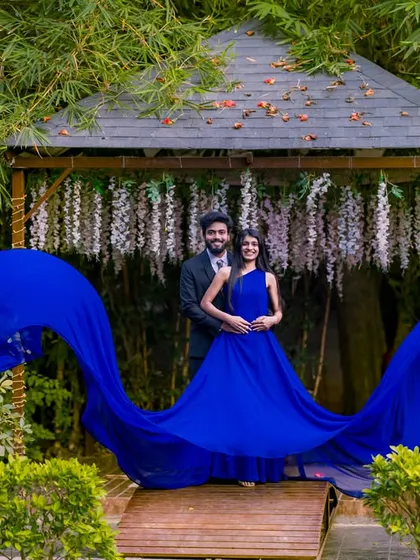 A dramatic shot of a flowing blue gown on the wooden bridge, creating a beautiful contrast with the green bamboo background.