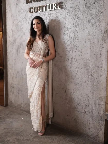 A full-length view of the ivory pre-draped sari, showcasing its sophisticated silhouette and the modern touch of a high slit.