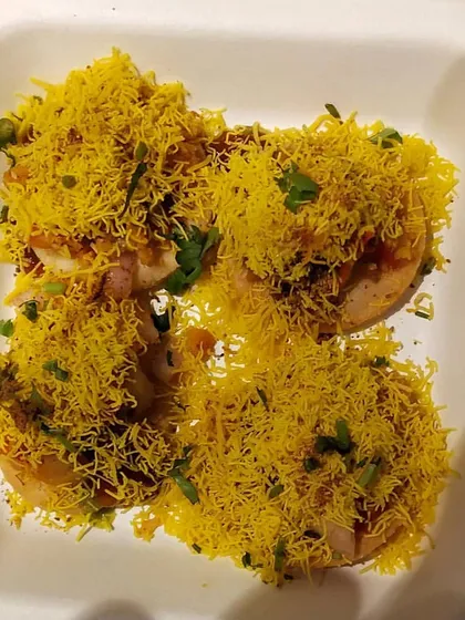 A close up of my freshly prepared Sev Puri. Each bite is a burst of flavor, made with crisp puris, tangy chutneys, and a generous topping of sev. It's a perfect example of the authentic Mumbai street food I can bring to your gathering.