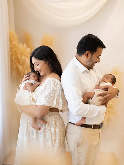 A loving glance between parents as they hold their precious twin newborns. This pose beautifully captures the partnership and shared joy of starting a new chapter as a family of four.