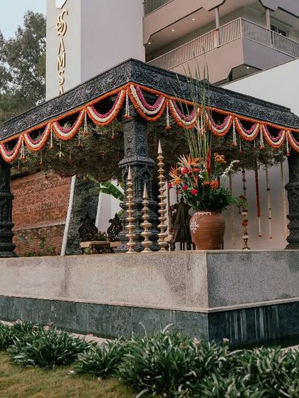 A stone-washed mandap designed to look like an ancient temple structure. Adorned with traditional flower garlands, it creates a sacred and timeless space for the wedding ceremony.