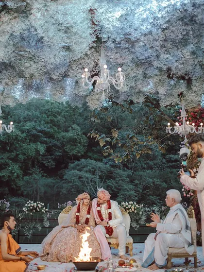 We created an enchanted forest setting for Neha and Tushar's ceremony. A canopy of delicate white flowers and elegant chandeliers hung above them, creating a magical, cloud-like effect that felt both intimate and otherworldly.