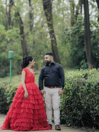 A candid moment within a cinematic shoot. As the couple walks hand-in-hand through a park path in Pune, her magnificent red dress adds a touch of drama to this otherwise natural interaction, blending two styles perfectly.