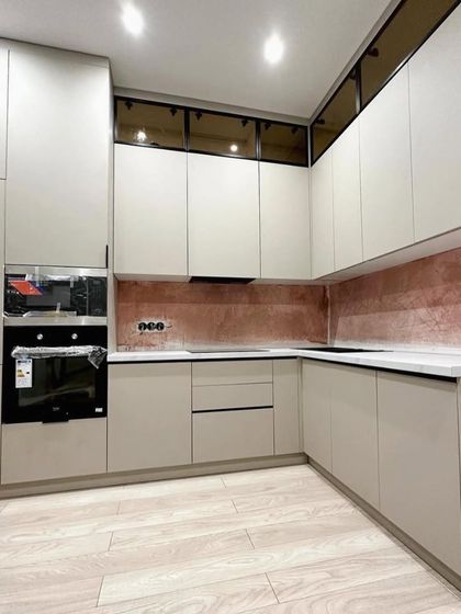 Another angle of the Palam Vihar kitchen, highlighting the seamless look of the handle-less cabinetry and the warm glow from the under-cabinet lighting against the unique backsplash.