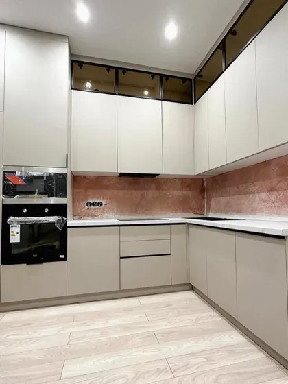 Another angle of the U-shaped kitchen, highlighting the ample counter space and the elegant combination of off-white cabinets, a white countertop, and a metallic backsplash.
