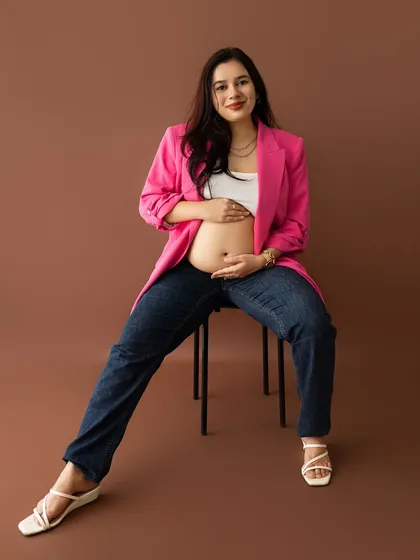 A chic and modern maternity look, featuring a mom-to-be in a bright pink blazer, white top, and jeans. This shows that maternity photos can be stylish, confident, and contemporary.