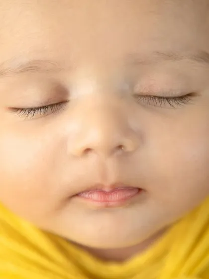 A macro shot of a newborn's face, so pure and serene. The yellow tones add a feeling of warmth and happiness to the portrait.