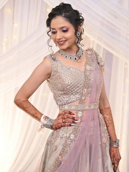 A client looking stunning in a pastel lavender and silver lehenga. The intricate beadwork on the blouse and the belted dupatta make it a modern and chic choice.