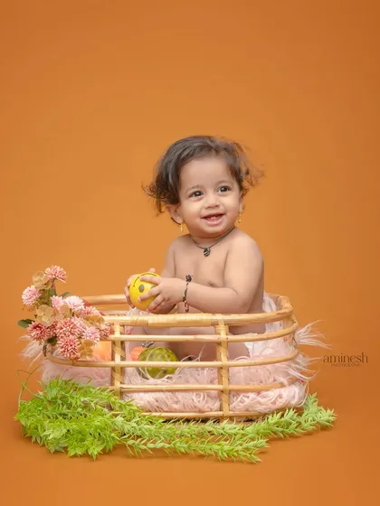 A happy baby boy playing in a wicker basket decorated with flowers and greenery. This is a classic and adorable setup for capturing baby's first few months.