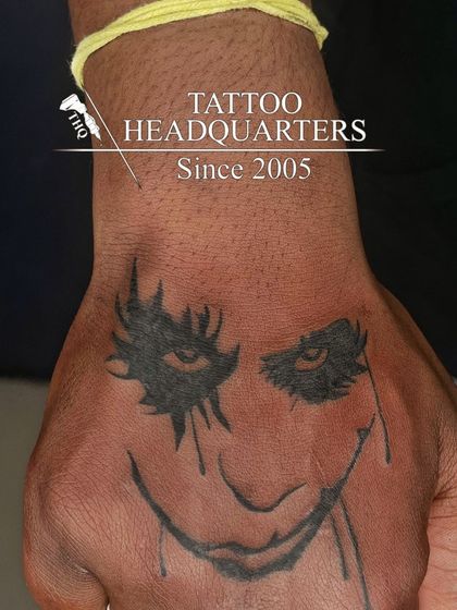 A stylized tattoo of the Joker's smile on the hand, a popular design from the world of comics.
