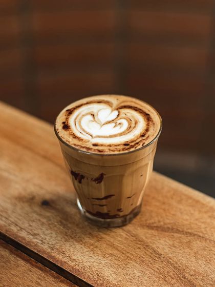 A beautifully crafted mocha or hot chocolate with intricate latte art, served in a glass.