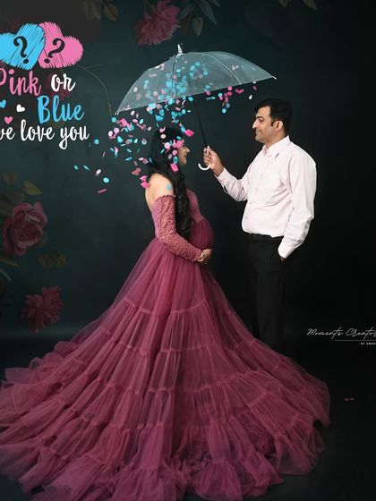 A creative gender reveal concept. The couple stands under an umbrella as blue and pink confetti rains down, a playful way to announce "Pink or Blue, we love you."