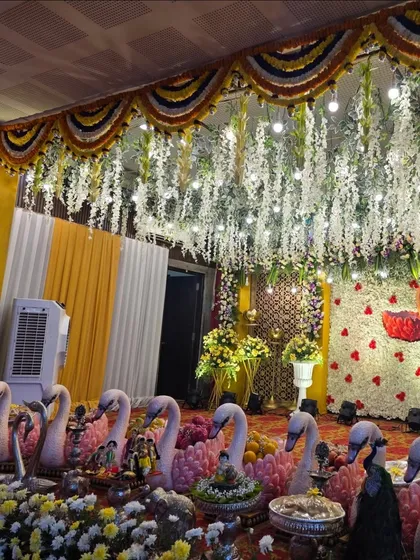 A full stage decorated with a swan theme, featuring a swan motif made of flowers on the backdrop and a row of swan props.