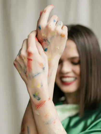 A joyful, out-of-focus shot capturing a genuine smile, with the focus on the color-stained hands, representing the playful nature of Holi.