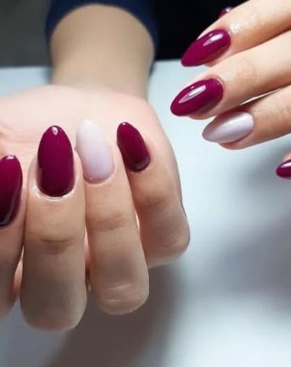 A sophisticated look with a mix of deep magenta and a single pale pink accent nail on an almond shape.