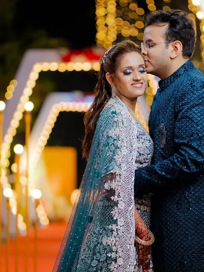 A sweet forehead kiss against a backdrop of beautiful fairy lights. This engagement photo is full of warmth and romance.