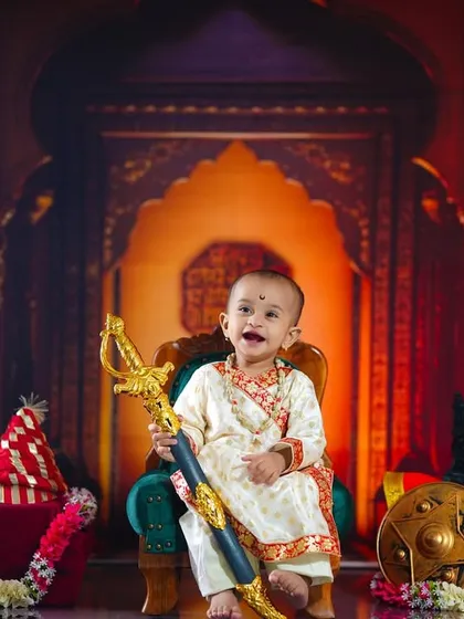 A joyful smile from our little Maharaj as he holds the toy sword, showing that even a royal photoshoot can be full of fun.