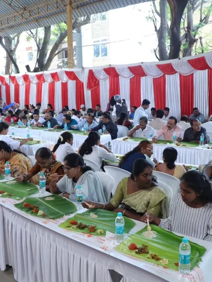 A wide view of a large wedding reception with guests seated in long rows, enjoying our traditional banana leaf catering. We are equipped to handle events of any scale, ensuring every guest is well-fed.