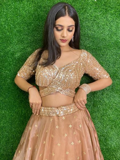 This rose gold lehenga with a unique crossover blouse is a modern and stylish option. The delicate leaf-pattern embroidery adds a touch of nature-inspired elegance.