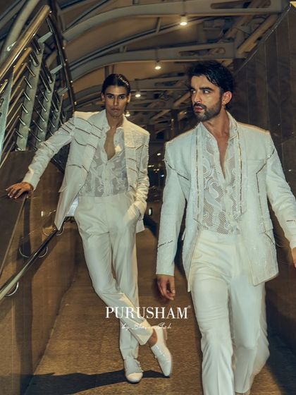 An all-white look from the 'Late Check Out' collection, proving that after-hours elegance isn't limited to dark colors. The focus here is on the sharp, power-shoulder silhouette and subtle linear embroidery, paired with a sheer, patterned shirt.