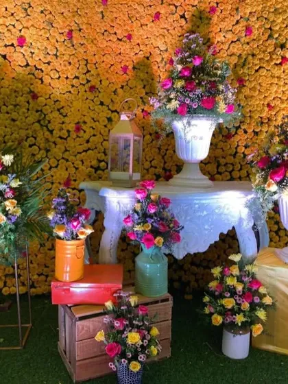 A detailed look at a decor corner for a Haldi event, featuring floral arrangements in white vases and colorful pots.