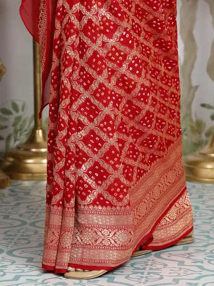 A detailed shot of the red saree's pallu, featuring a classic Banarasi weave and Bandhani pattern.