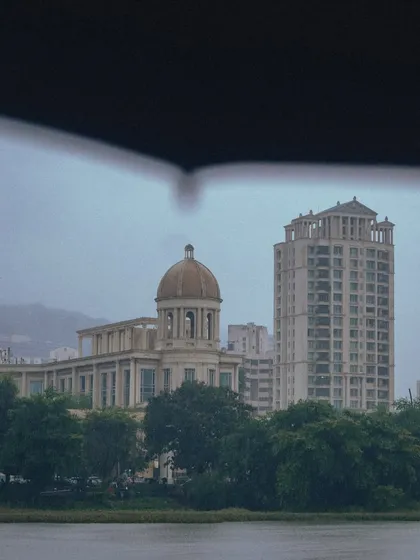A view of Hiranandani, Powai, framed by an umbrella. The architecture looks almost like a painting through the soft, grey light of the monsoon.