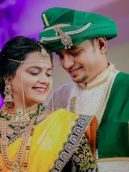 A beautiful portrait of a Maharashtrian couple, their smiles reflecting the joy of the occasion. The bride's yellow saree and the groom's green turban add a wonderful splash of color.