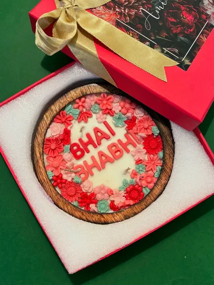 A beautiful blend of fragrance, design, and emotion. This handcrafted floral candle says 'Bhai Bhabhi' and is set in a wooden bowl, making it a unique and memorable Rakhi gift.