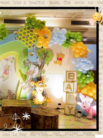 A detailed view of the main stage, featuring Pooh, Tigger, and Piglet, 'BABY' blocks, and a honeycomb-patterned balloon arch.