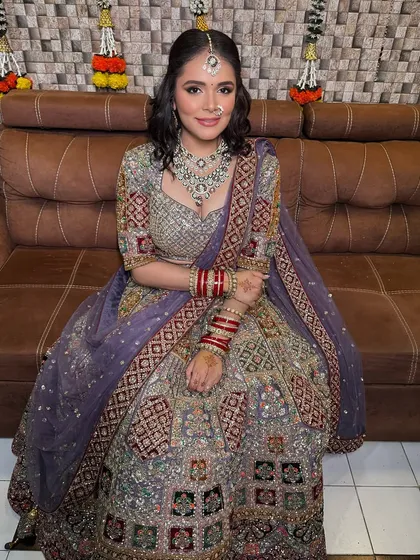 A full-length shot of the bride seated, showcasing her beautiful lavender lehenga and sparkling jewellery.