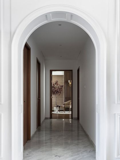 We love using architectural elements like arches to create visual interest. This simple white arch frames the view into the next room, adding depth and a touch of classic elegance to the corridor.