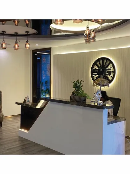 The final constructed reception area for SVG Exports, showing the interplay of ambient and accent lighting. The backlit company logo, marble-topped desk, and reflective ceiling create a sense of luxury and established presence.