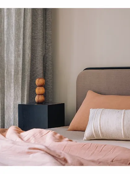 We love playing with subtle color combinations. In this bedroom, a purple yam toned headboard and tangerine bedding blend effortlessly with warm sand walls. The result is a soft, inviting space where colors and textures create a feeling of serene comfort.
