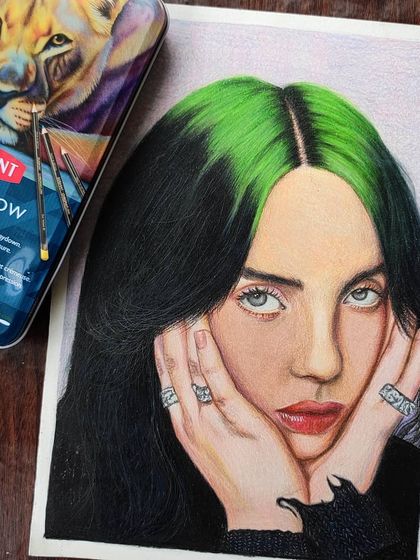 The Billie Eilish portrait shown with the Derwent Chromaflow pencil tin, highlighting the professional materials used for this piece.